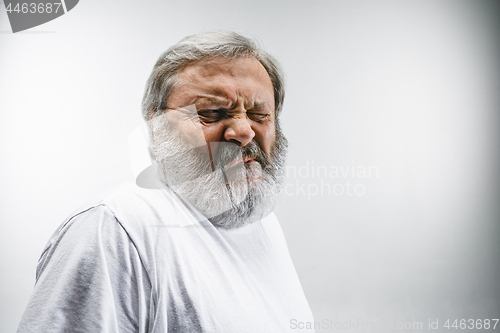 Image of Senior man with disgusted expression repulsing something on white