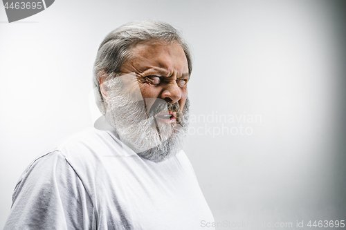 Image of Senior man with disgusted expression repulsing something on white