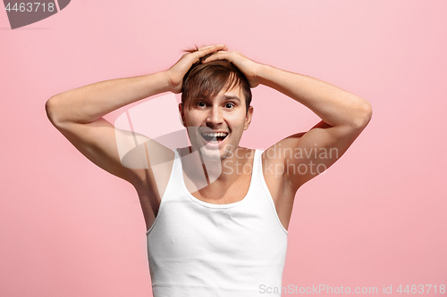 Image of The happy man standing and smiling against pink background.