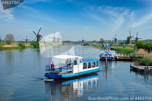 Image of Netherlands rural lanscape with tourist boat and windmills at famous tourist site Kinderdijk in Holland