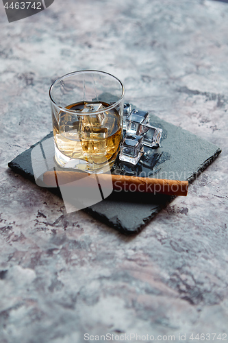 Image of Glass of whiskey with ice cubes and cigar