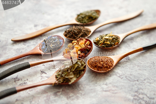 Image of Virious kinds of tea in wooden spoons on stone table