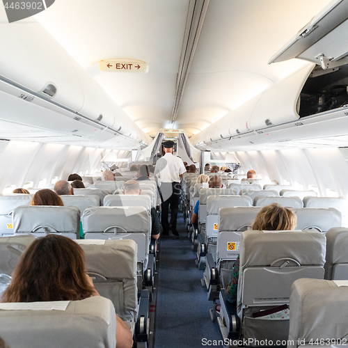 Image of Interior of commercial airplane with passengers on their seats during flight.