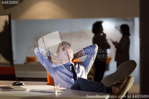 Image of businessman sitting with legs on desk at office