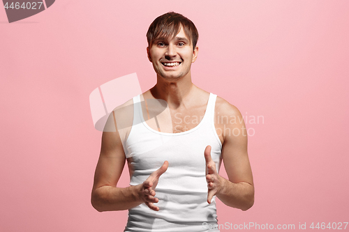 Image of The happy man standing and smiling against pink background.