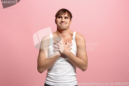 Image of The happy man standing and smiling against pink background.