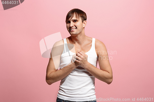 Image of The happy man standing and smiling against pink background.