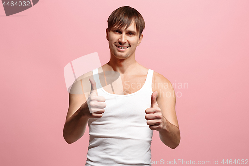 Image of The happy man standing and smiling against pink background.