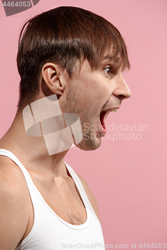 Image of The young emotional angry man screaming on pink studio background