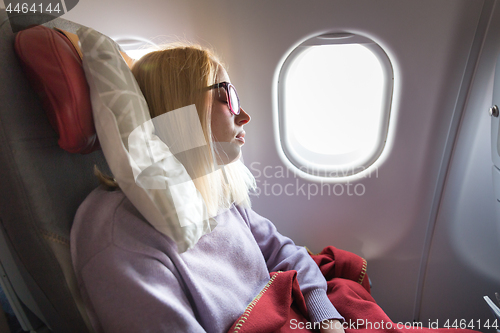 Image of Tired blonde casual caucasian lady sleepin on seat while traveling by airplane. Commercial transportation by planes.