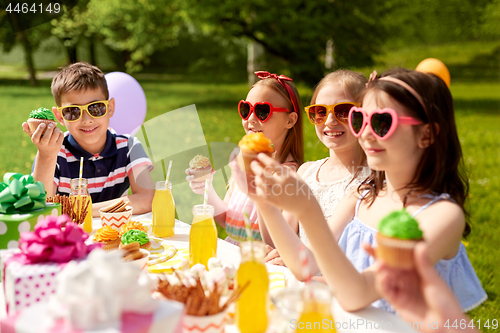 Image of kids eating cupcakes on birthday party in summer