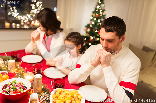 Image of family praying before meal at christmas dinner