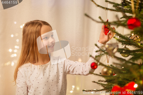 Image of happy girl in red dress decorating christmas tree