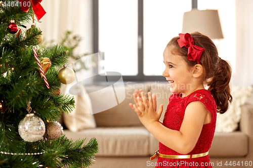 Image of little girl decorating christmas tree at home