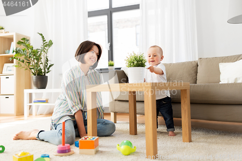 Image of happy mother with little baby boy playing at home