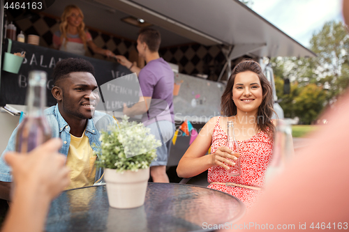 Image of friends with drinks sitting at table at food truck