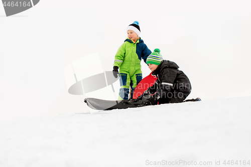 Image of kids sliding on sleds down snow hill in winter