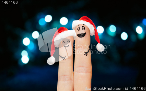 Image of finger couple in santa hats over lights