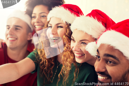 Image of happy friends in santa hats at christmas party