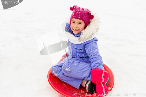 Image of happy little girl with snow saucer sled in winter