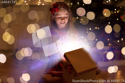 Image of smiling girl opening christmas gift at night