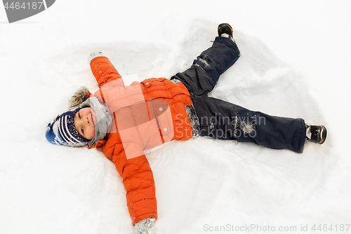 Image of happy little boy making snow angels in winter