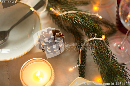 Image of pine cone and candle burning on christmas table