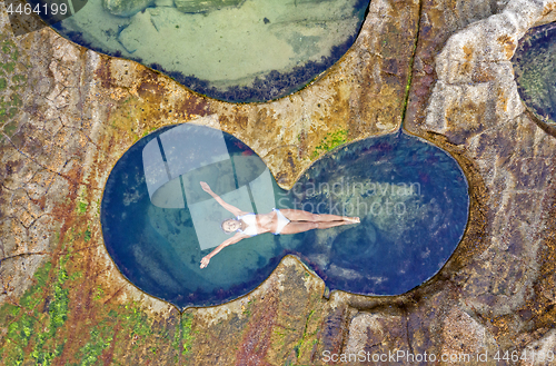 Image of Female floating in idyllic ocean rock pool just bliss