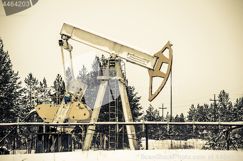 Image of Pump jack situated in forest.