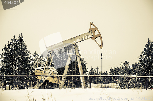 Image of Pump jack situated in forest.