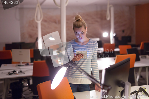 Image of woman working on digital tablet in night office