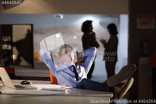 Image of businessman sitting with legs on desk at office