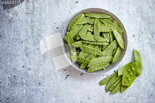 Image of Fresh green peas in white ceramic bowl on gray stone background