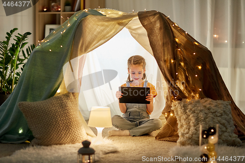 Image of little girl with tablet pc in kids tent at home