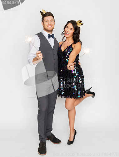 Image of happy couple with crowns and sparklers at party