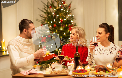 Image of happy friends having christmas dinner at home