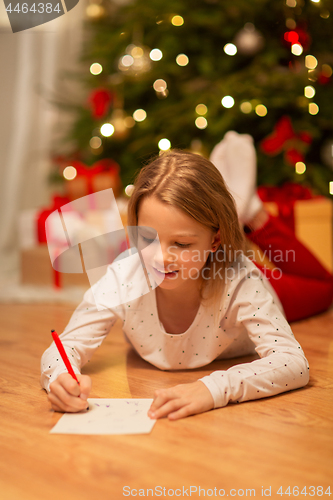 Image of smiling girl writing christmas wish list at home