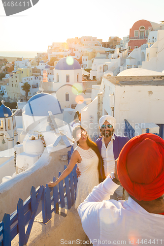 Image of Indian tourists taking photos of colorful Oia village on Santorini island, Greece.