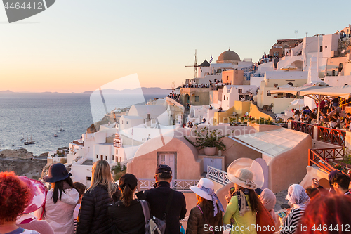 Image of Indian tourists taking photos of colorful Oia village on Santorini island, Greece.