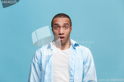 Image of The young attractive man looking suprised isolated on blue