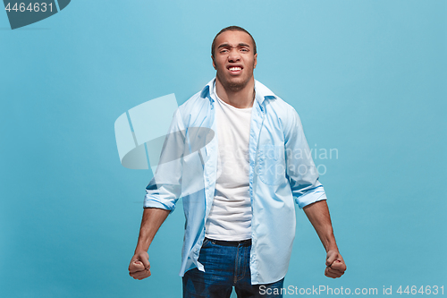 Image of The young emotional angry man screaming on blue studio background