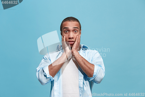 Image of The young attractive man looking suprised isolated on blue