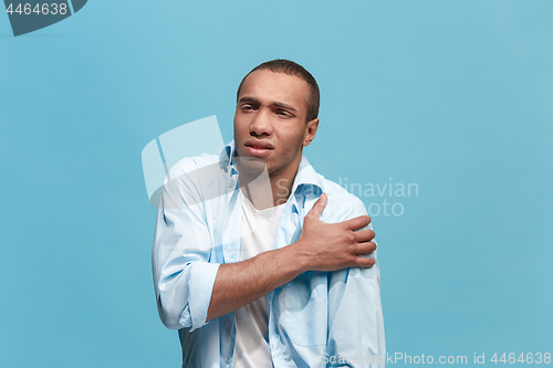 Image of Young man overwhelmed with a pain in the shoulder .