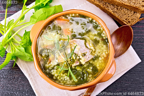 Image of Soup with couscous and spinach in clay bowl on board top