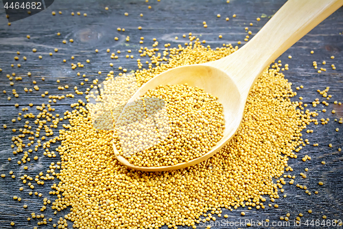 Image of Mustard seeds in wooden spoon on black board