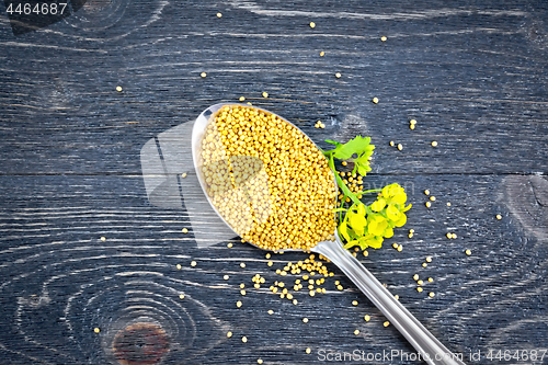 Image of Mustard seeds in metal spoon with flower on board top