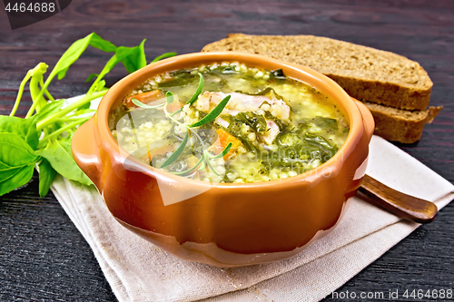 Image of Soup with couscous and spinach in clay bowl on wooden table