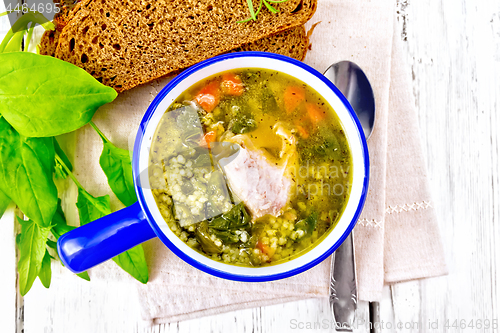 Image of Soup with couscous and spinach in blue bowl on board top