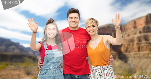 Image of happy friends hugging over grand canyon