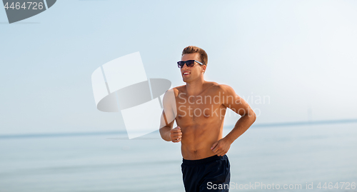 Image of happy man running along summer beach